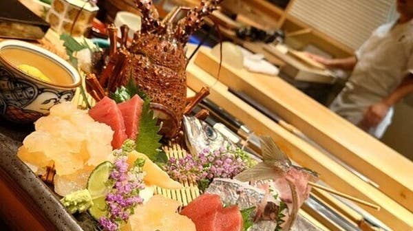 黒い石の台に伊勢海老が丸ごと乗った豪快な刺し身の盛り合わせ